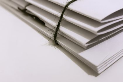 Pile of white envelopes tied with a green string, showcasing a minimalist design.