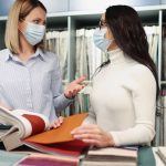Kobiety w ochronnych maskach medycznych przeglądają katalog próbek tkanek w sklepie podczas pracy