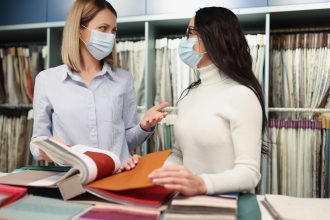 Kobiety w ochronnych maskach medycznych przeglądają katalog próbek tkanek w sklepie podczas pracy