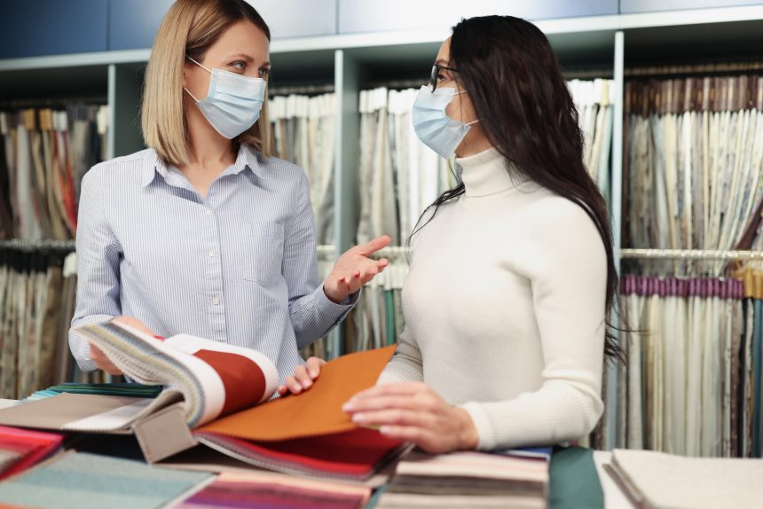 Kobiety w ochronnych maskach medycznych przeglądają katalog próbek tkanek w sklepie podczas pracy