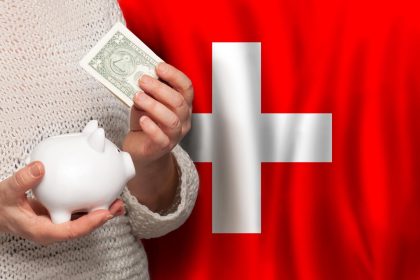 Szwajcarka z bankiem pieniężnym na tle szwajcarskiej flagi