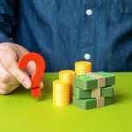 Znak zapytania obok stosu pieniędzy. Gdzie inwestować i jak chronić oszczędności przed inflacją, planowanie finansowe, bezpieczne aktywa, strategia zarządzania majątkiem osobistym.