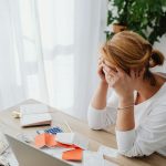 Woman stressed over financial receipts at a desk, dealing with expenses and calculations.
