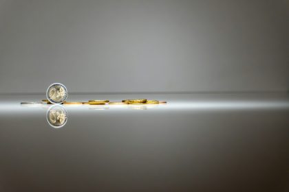 a pair of gold coins sitting on top of a reflective surface