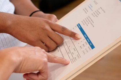 Two people pointing at financial details on a document, highlighting invoice analysis.