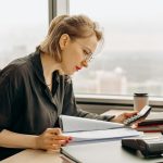 Woman accountant calculating financial documents at office desk.