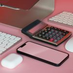 a desk with a keyboard, mouse, and cell phone