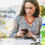Kobieta używająca telefonu komórkowego przy stole w restauracji