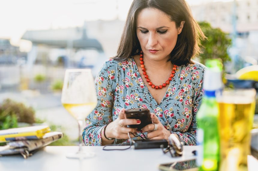 Kobieta używająca telefonu komórkowego przy stole w restauracji