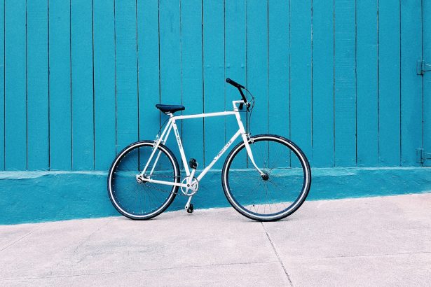 white road bike leaning on teal wooden wall during daytime