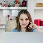 a woman sitting in front of a laptop computer