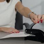 woman in white shirt holding pen writing on white paper