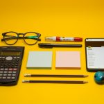 a calculator, pen, eyeglasses, notepad, pencils