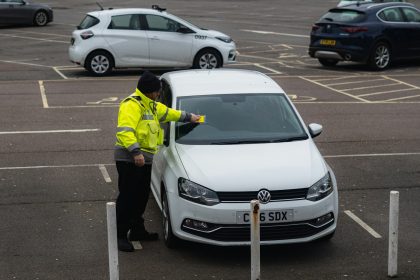 man in yellow jacket standing beside white car